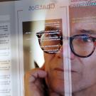 Close up photograph of a mature man studying a see-through computer monitor that’s displaying text provided by AI 